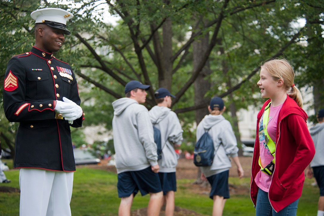 Sgt. Justin Creasman, Marine Barracks Washington ceremonial hoster, speaks with a spectator before the start of a Tuesday Sunset Parade at the Marine Corps War Memorial in Arlington, Va., June 5.
