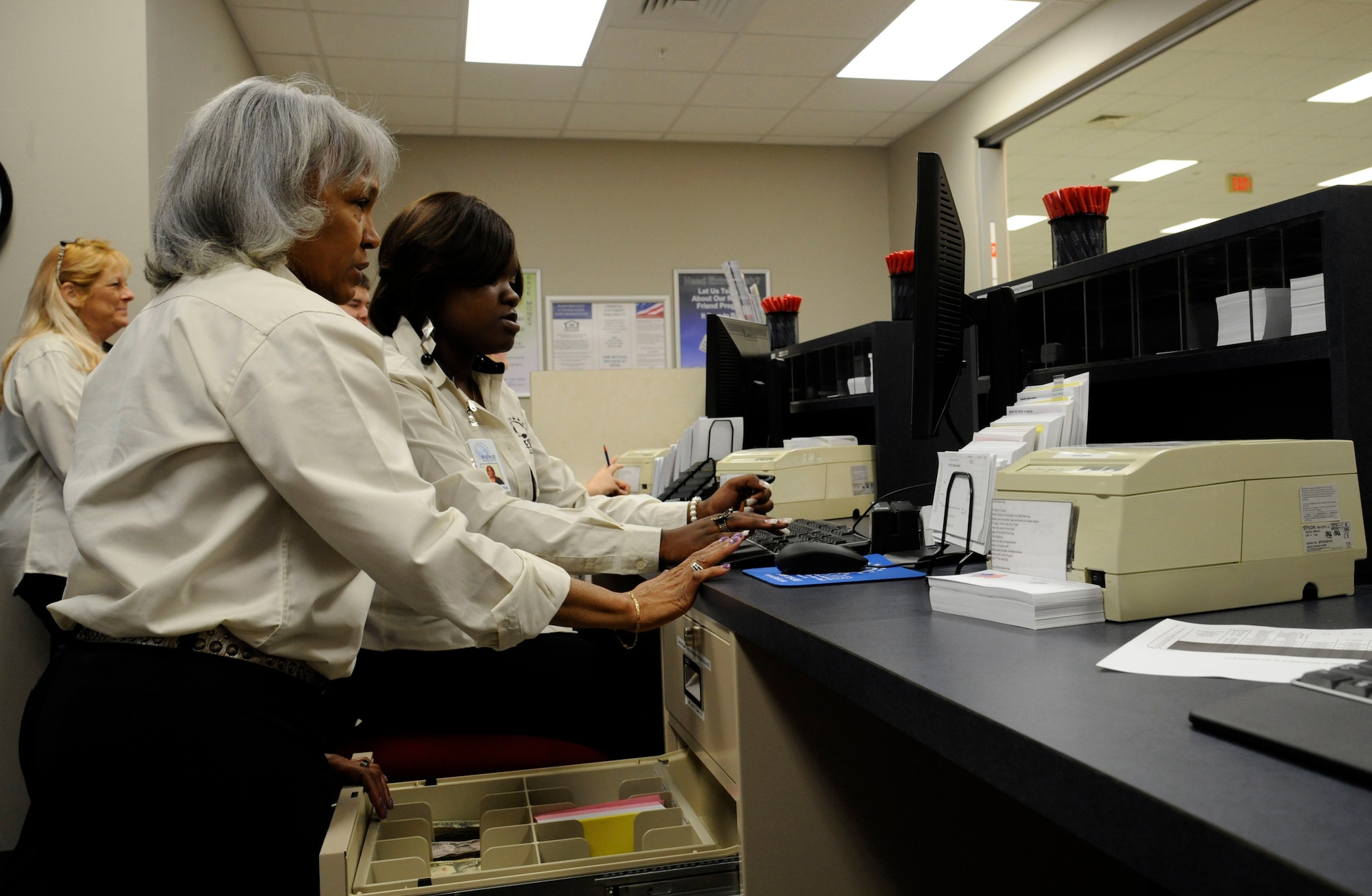 Shirley Calton and Shabarbara West, employees of Fort Sill National Bank, set up a cash drawer on Barksdale Air Force Base, La., June 6. Calton trained West in her responsibilities as a customer service representative which will include opening bank accounts, cashing checks and giving business plan advice. (U.S. Air Force photo/Airman 1st Class Andrew Moua)(RELEASED)
