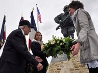 World War II veteran Al Mambre receives a floral arrangement to place at the base of the recently unveiled memorial to Army Maj. Richard “Dick” Winters June 6, 2012, near Utah Beach, France. Mambre, a member of the famed “Easy” Company, 2nd Battalion, 506th Parachute Infantry Regiment of the 101st Airborne Division, was joined by other World War II veterans and more than 200 attendees to unveil a statue dedicated to Winters. The memorial eulogizes Winter’s unwavering commitment to the soldiers he was assigned and the leadership young officers and noncommissioned officers showcased during battle in Europe. Winters and his company were made famous by the New York Times bestseller and same-titled television series “Band of Brothers” that documents the Airborne paratroopers’ time fighting in France, Holland and Germany. (U.S. Air Force photo/Staff Sgt. Stephen J. Collier)