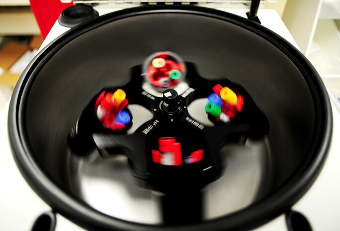 After blood is drawn in the phlebotomy lab, the withdrawn blood is brought to the centrifuge machine. The machine rotates the fluids with the lid closed, at a high rotating speed around a center axis separating the fluids from the solids with centrifugal force. Red blood cells are denser than plasma cells and during the centrifugal process the two are separated for further testing. (U.S. Air Force photo / Senior Airman Dennis Sloan)