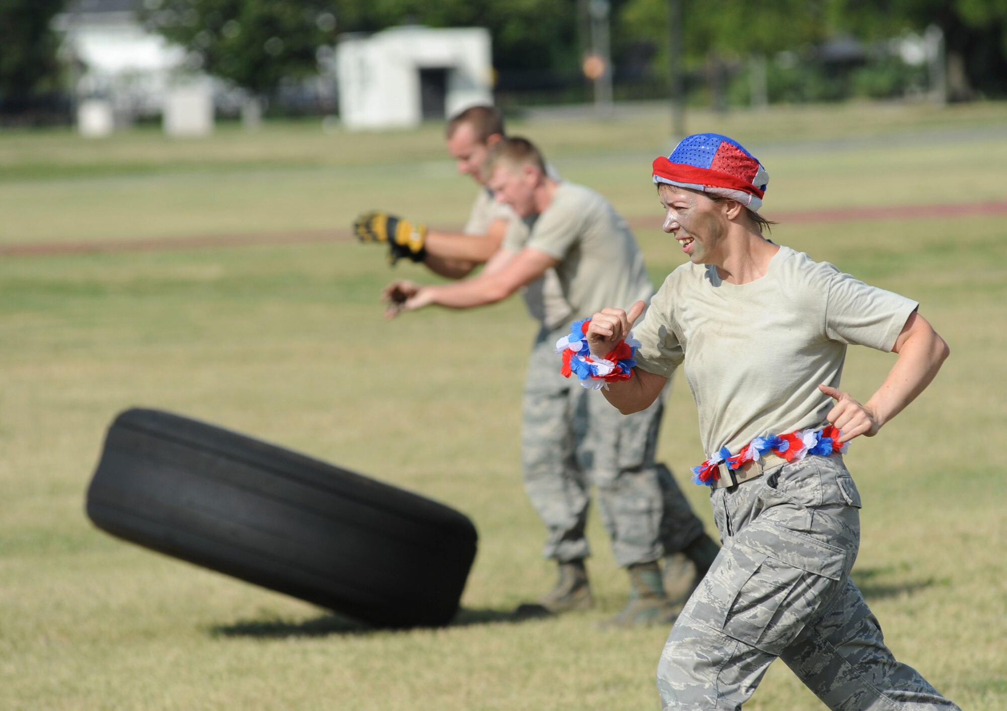 Tech. Sgt. Walter Sutler and Airman 1st Class Kyle Ledford, 81st Infrastructure Division and members of team Fire Dawgs compete in the “Tire Toss” challenge as Master Sgt. Casy Boomershine, a member of team Logitators from the 81st Logistics Readiness Squadron, races to meet her other team mates to assist in completing the challenge during the 81st Mission Support Group Ultimate Warrior Challenge June 1, 2012, at the Triangle Track at Keesler Air Force Base, Miss.  The challenge was held in honor of fellow service members who lost their lives in the fight for our nation’s freedom. It consisted of nine four-member teams racing in a competition designed to take them through various aspects of a deployment.  (U.S. Air Force photo by Kemberly Groue)