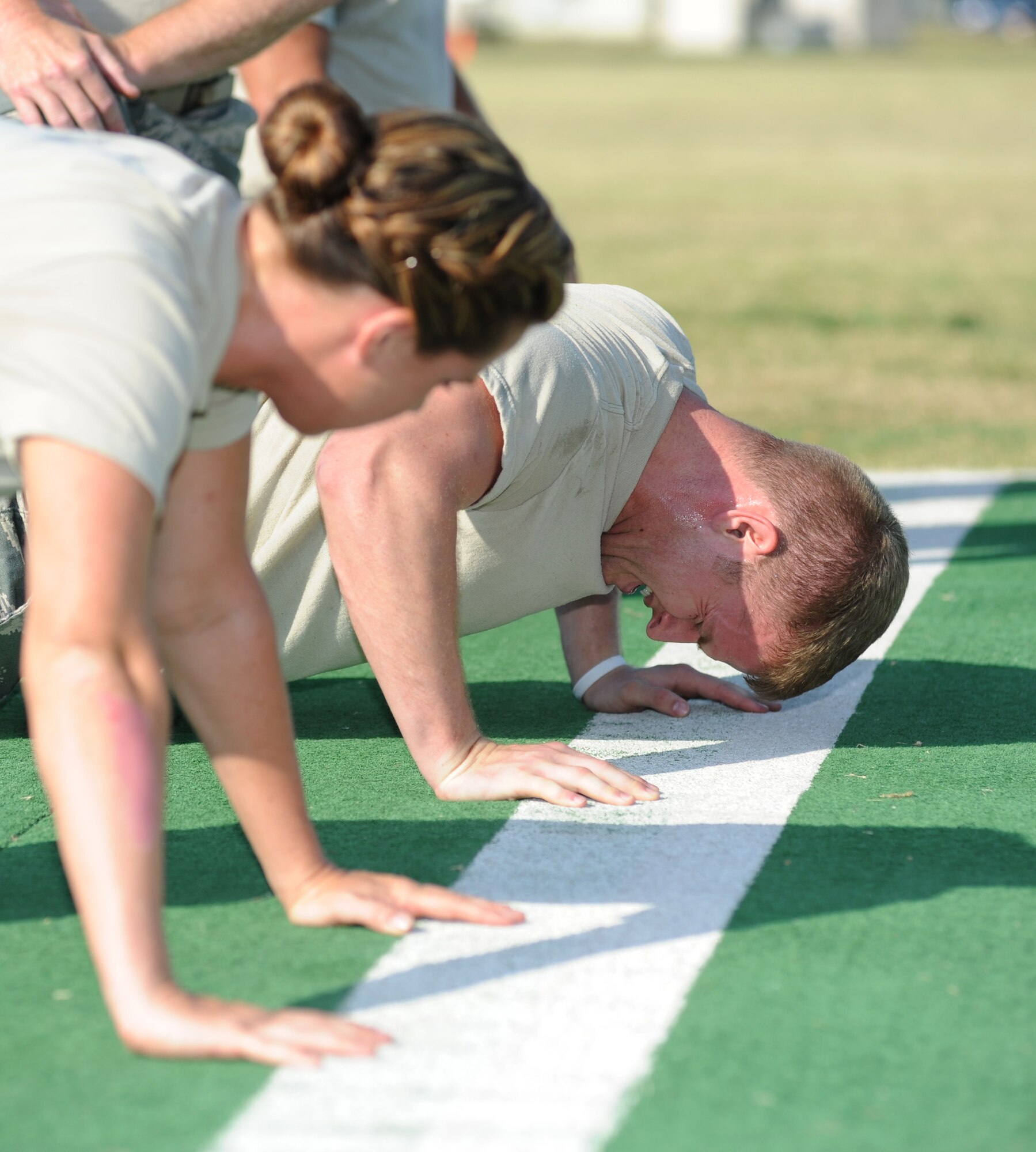 Bad Intentions team members from the 81st Security Forces Squadron, Staff Sgt. Amanda Green waits for her turn to do pushups as Senior Airman Chance Telford completes his turn in the “Pre-deployment Fitness Test” challenge in which each team performs 400 total Air Force regulation pushups with only one team member doing them at a time during the 81st Mission Support Group Ultimate Warrior Challenge June 1, 2012, at the Triangle Track at Keesler Air Force Base, Miss.  The challenge was held in honor of fellow service members who lost their lives in the fight for our nation’s freedom. It consisted of nine four-member teams racing in a competition designed to take them through various aspects of a deployment.  (U.S. Air Force photo by Kemberly Groue)
