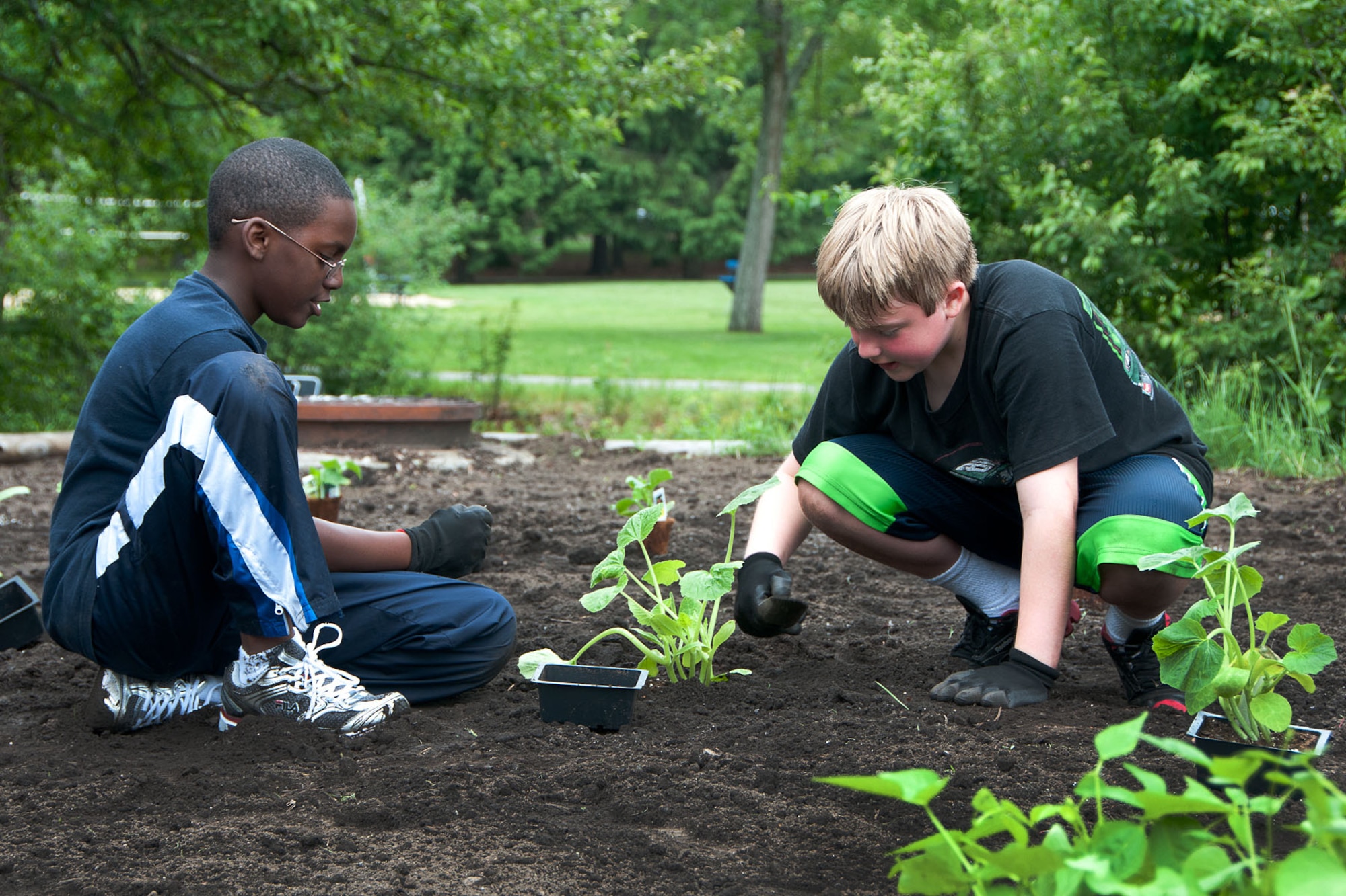 HANSCOM AIR FORCE BASE, Mass. – Nicholas Reid (left) and Aiden Herzog work in the community garden near the Youth Center May 30. In addition to the youth, volunteers from US Family Health Plan assisted in planting flowers, vegetables and herbs in the garden for Hanscom children to enjoy all summer long. (U.S. Air Force photo by Linda LaBonte Britt) 
