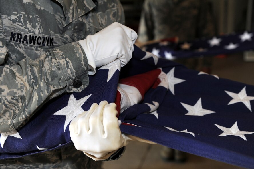 U.S. Air Force Senior Airman Ridge Krawczyk, 18th Component Maintenance Squadron intermediate avionics team member, holds the American flag during the flag folding portion of honor guard practice Apr. 25, on Kadena Air Base, Japan. The honor guard members folded the flag step by step to ensure the new members understood how to fold the flag. (U.S. Air Force photo/Junko Kinjo)