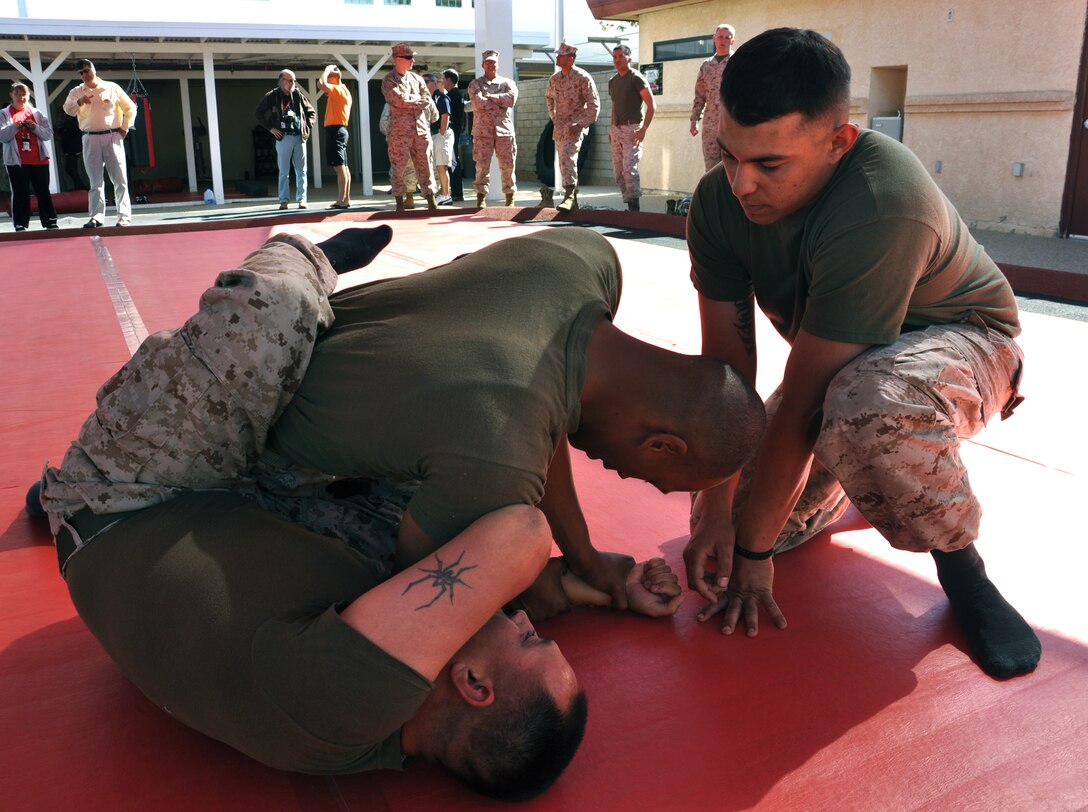 Cpl. Brian Chandronnet observes Sgt. Anthony Villalobos, assistant chief for S-3 and S-4 and Cpl. Sir Edward Daniels, an armorer, with Headquarters Battalion aboard Marine Corps Logistics Base Barstow, grapple during the grand opening of the new martial arts training facility aboard MCLB Barstow, June 6.
