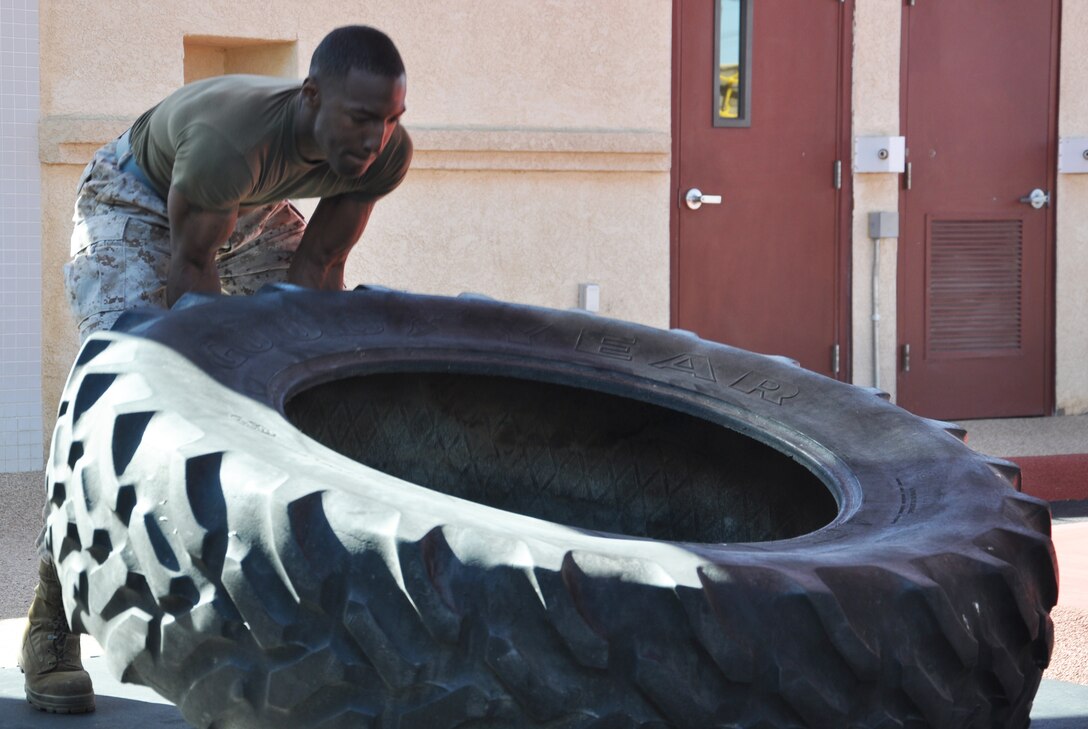 Lance Corporal Aaron Thornton, a calibration technician with Fleet Support Division stationed aboard Marine Corps Logistics Base Barstow, flips a tire for physical conditioning during the grand opening of the new martial arts training facility aboard the installation June 6.