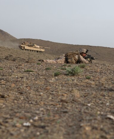 A tank drives by to provide better security for the Marines with Charlie Company, 1st Battalion, 8th Marine Regiment, as they prepare to search a village for Taliban fighters in the early morning, April 18, 2012. The Marines and sailors with Charlie Co. took part in a month long operation where they cleared the Gostan valley of enemy forces.