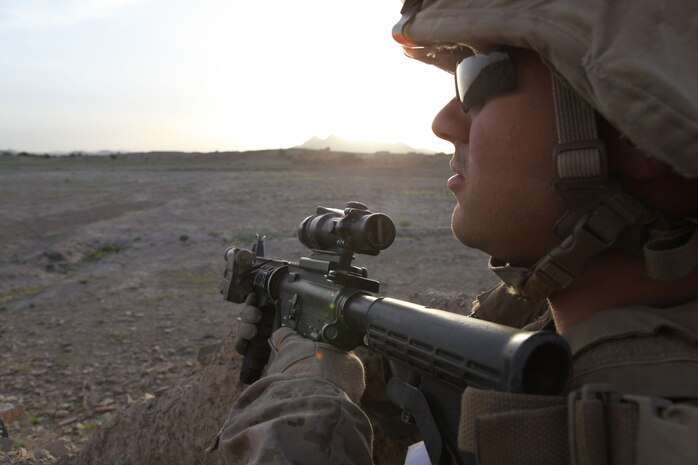 A Marine with Charlie Company, 1st Battalion, 8th Marine Regiment, looks over at a village as the sun rises on the first day of their operation, April 17, 2012. The Marines and sailors with Charlie Company took part in a month long operation where they cleared the Gostan valley of enemy forces.