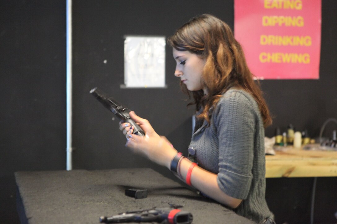 A girl reloads her weapon at an Indoor Simulated Marksmanship Trainer aboard Marine Corps Base Camp Lejeune, June 1. The girl was there with Wilderness Way Girls Camp.  