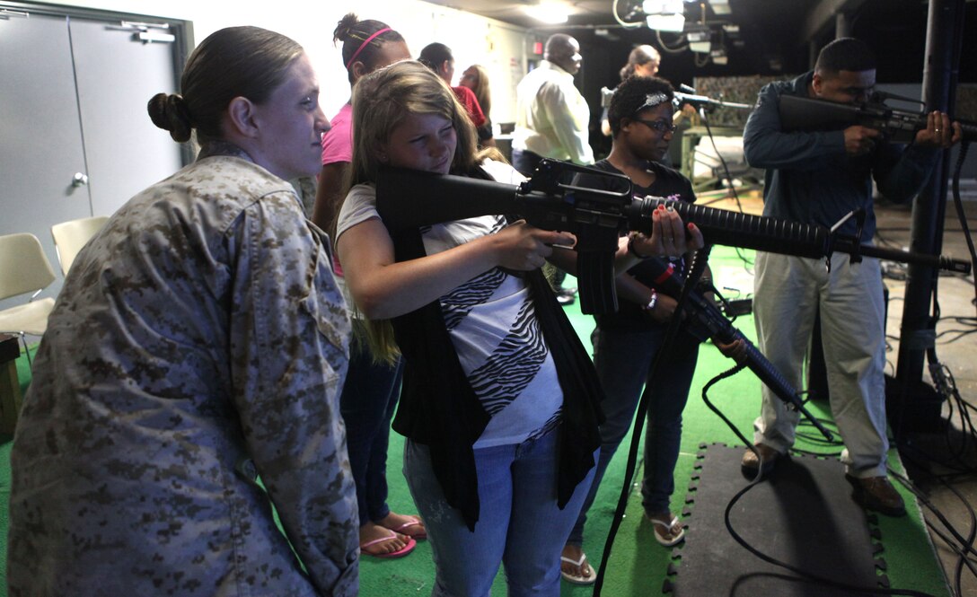 Cpl. Christina Hataway, an armory custodian with Headquarters and Support Battalion, looks over a girls form before offering advice at an Indoor Simulated Marksmanship Trainer aboard Marine Corps Base Camp Lejeune, June 1. Hataway acted as a role model to the girls from Wilderness Way Girls Camp. 