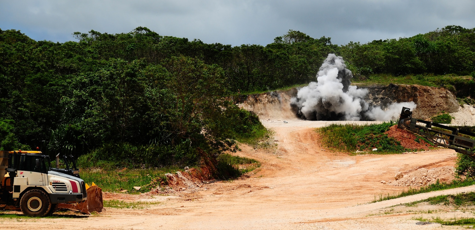 A loud boom fills the quarry as three explosives were detonated simultaneously at the RED HORSE quarry, June 6. The 554th RED HORSE Squadron explosive demolition team blasts once a month to stay qualified and at least once a quarter to obtain raw material from the quarry. (U.S. Air Force photo by Airman 1st Class Marianique Santos/Released)