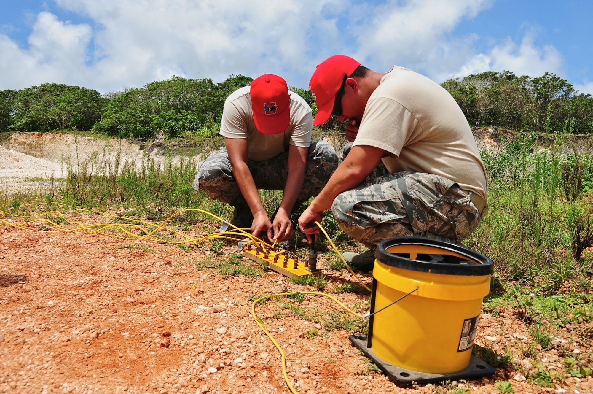 The 554th RED HORSE Squadron explosive demolition team members connect the explosives’ wires to the sequential board during set up for a blast at the RED HORSE quarry, June 6.  The team blasts once a month to stay qualified and at least once a quarter to obtain raw material from the quarry. (U.S. Air Force photo by Airman 1st Class Marianique Santos/Released)