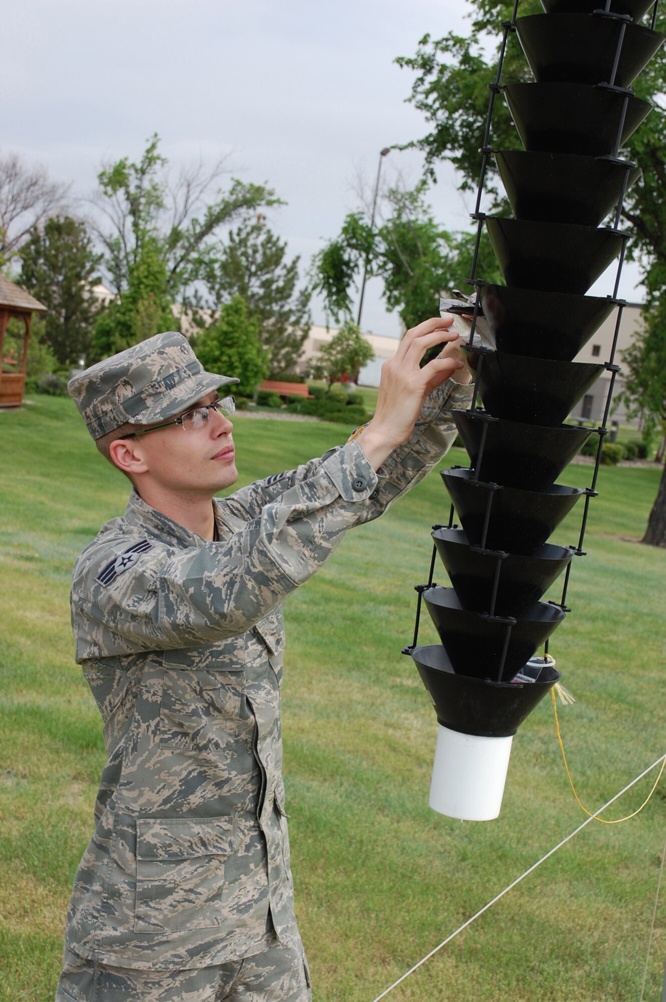 Senior Airman Brandon Biehn, 341st Civil Engineer Squadron pest management technician, checks the pheromone packs in a beetle trap on Malmstrom Air Force Base June 5.  These traps, provided by the U.S. Forest Service, are being used at five different bases to help with beetle classification. (U.S. Air Force photo/Senior Airman Kristina Overton)
