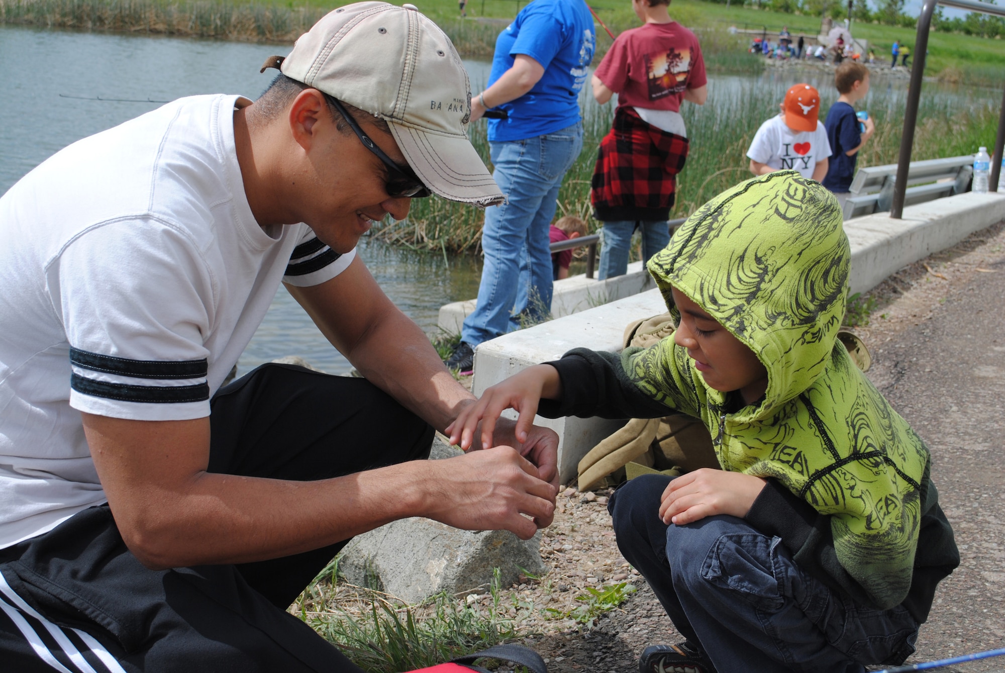 Staff Sgt. Mark Tigbao, 819th RED HORSE Squadron utilities member, shows his son Keean, 6, how to put a worm onto a fishing hook. For some children, this event was their first time fishing. (U.S. Air Force photo/Airman 1st Class Cortney Paxton)