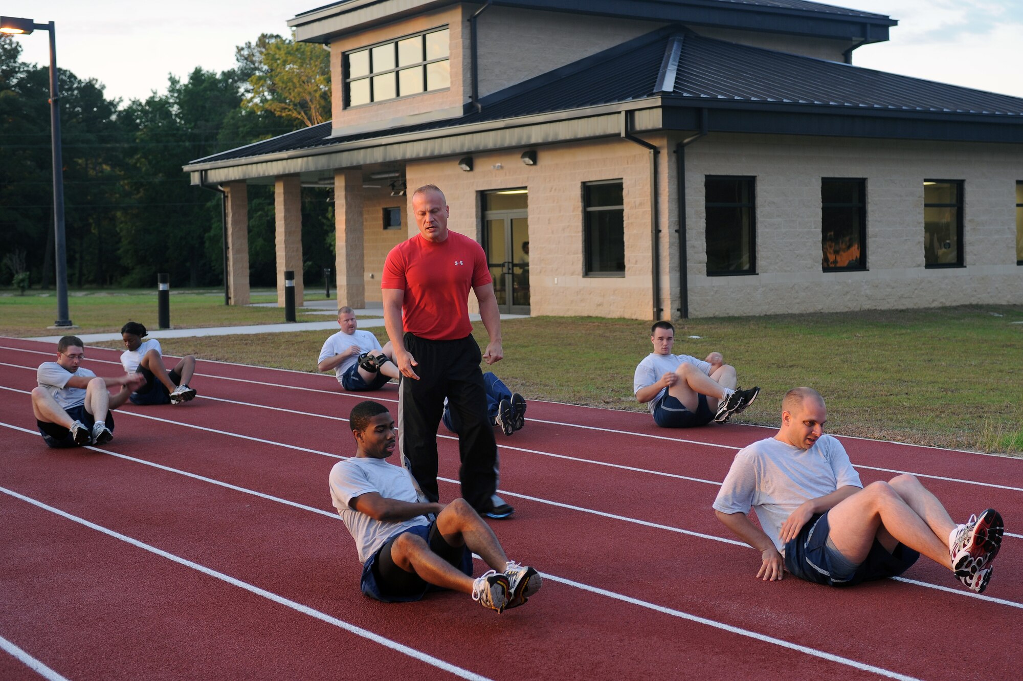 Mike Unden watches Airmen as they perform mason twists during the wing Fitness Improvement Training program on the quarter-mile track on Seymour Johnson Air Force Base, N.C., June 6, 2012. Mason twists open up the oblique muscles while conditioning abdominal muscles. Unden, 4th Force Support Squadron military fitness specialist, is from Wichita, Kan. (U.S. Air Force photo/Airman 1st Class John Nieves Camacho/Released)