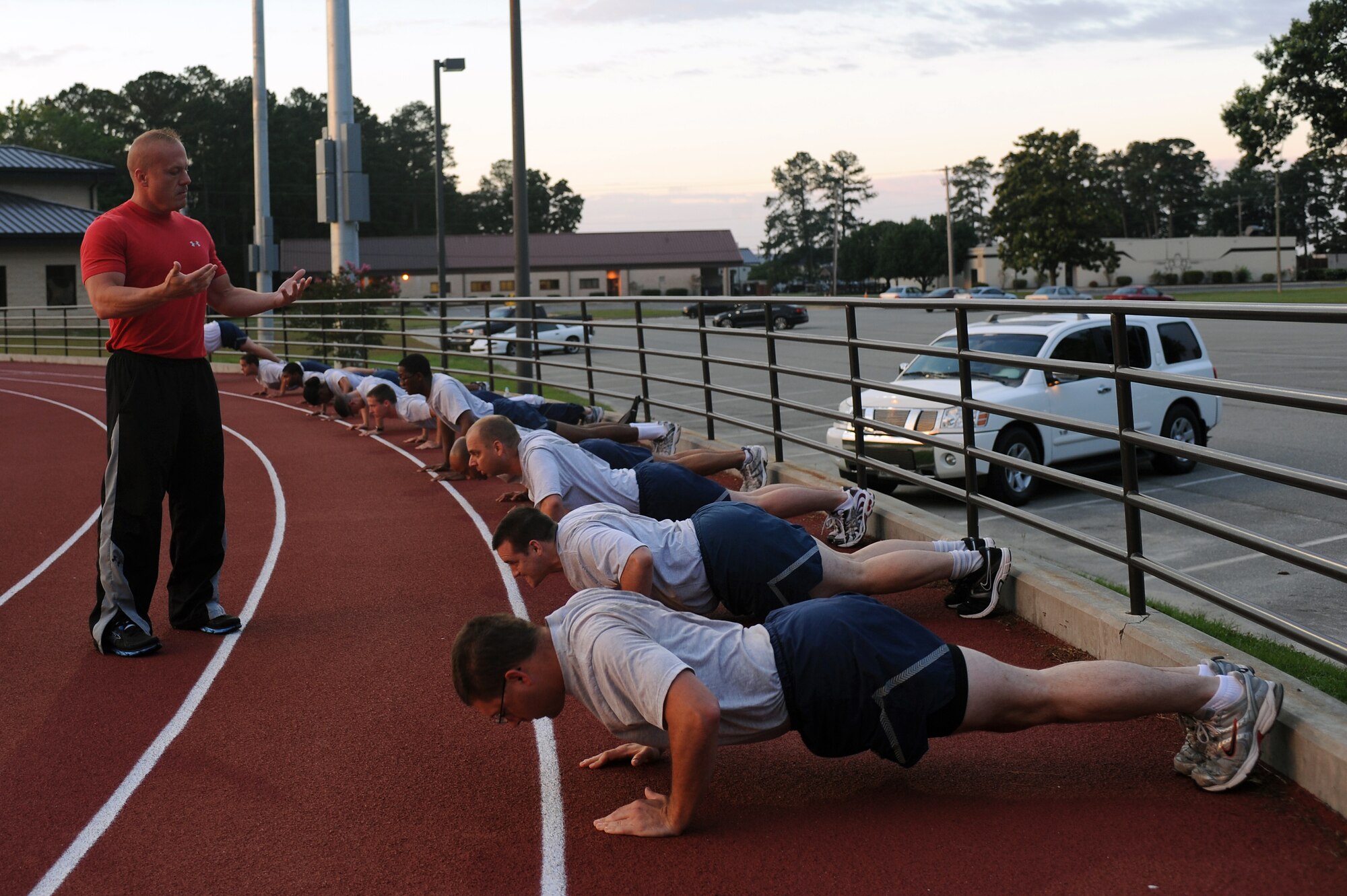 Mike Unden counts cadence as Airmen do push-ups during the wing Fitness Improvement Training program at the quarter-mile track on Seymour Johnson Air Force Base, N.C., June 6, 2012. Class members do push-ups to prepare themselves for their physical fitness assessment where they have one minute to complete a set amount of repetitions. Unden, 4th Force Support Squadron military fitness specialist, is from Wichita, Kan. (U.S. Air Force photo/Airman 1st Class John Nieves Camacho/Released)