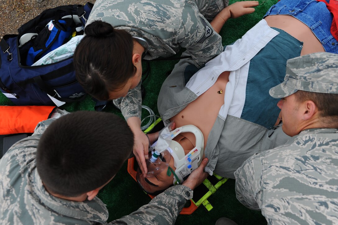 Staff Sgt Mellisa McQuagge (middle), 28th Medical Group ambulance services technician, teams up with Staff Sgt. John Vasquez (right) and Airman 1st Class Jared Weeks, 28th Civil Engineer Squadron fire protection specialists, to stabilize and treat a human patient simulator during a motorcycle crash exercise at Ellsworth Air Force Base, S.D., May 23, 2012. Airmen trained to improve their ability to respond to various scenarios, and treat simulated patients that can mimic human symptoms and responses. (U.S. Air Force photo by Airman 1st Class Zachary Hada/Released)