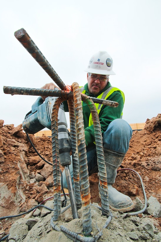 Luis Vasquez, with Forrester Construction Company, chips excess concrete from one of the 433 concrete piles set in place to support the new columbarium being built at Arlington National Cemetery.   The new 62,640 square-foot facility will provide more than 20,000 niche spaces to inurn military, former military and other personnel who qualify for inurnment at the cemetery. (U.S. Army photo/Patrick Bloodgood)