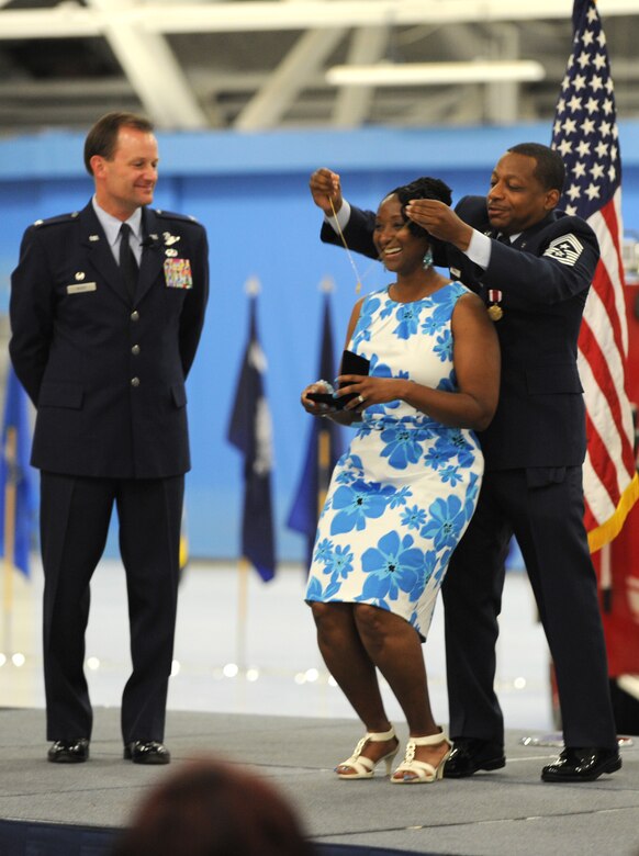 Chief Master Sgt. Anthony Brinkley, 11th Wing/Joint Base Andrews command chief, clasps a necklace around his wife's neck during his retirement ceremony June 8, 2012.  The necklace served to commemorate Mrs. Brinkley's service as an Air Force spouse.  (U.S. Air Force Photo by Staff Sgt. Torey Griffith)