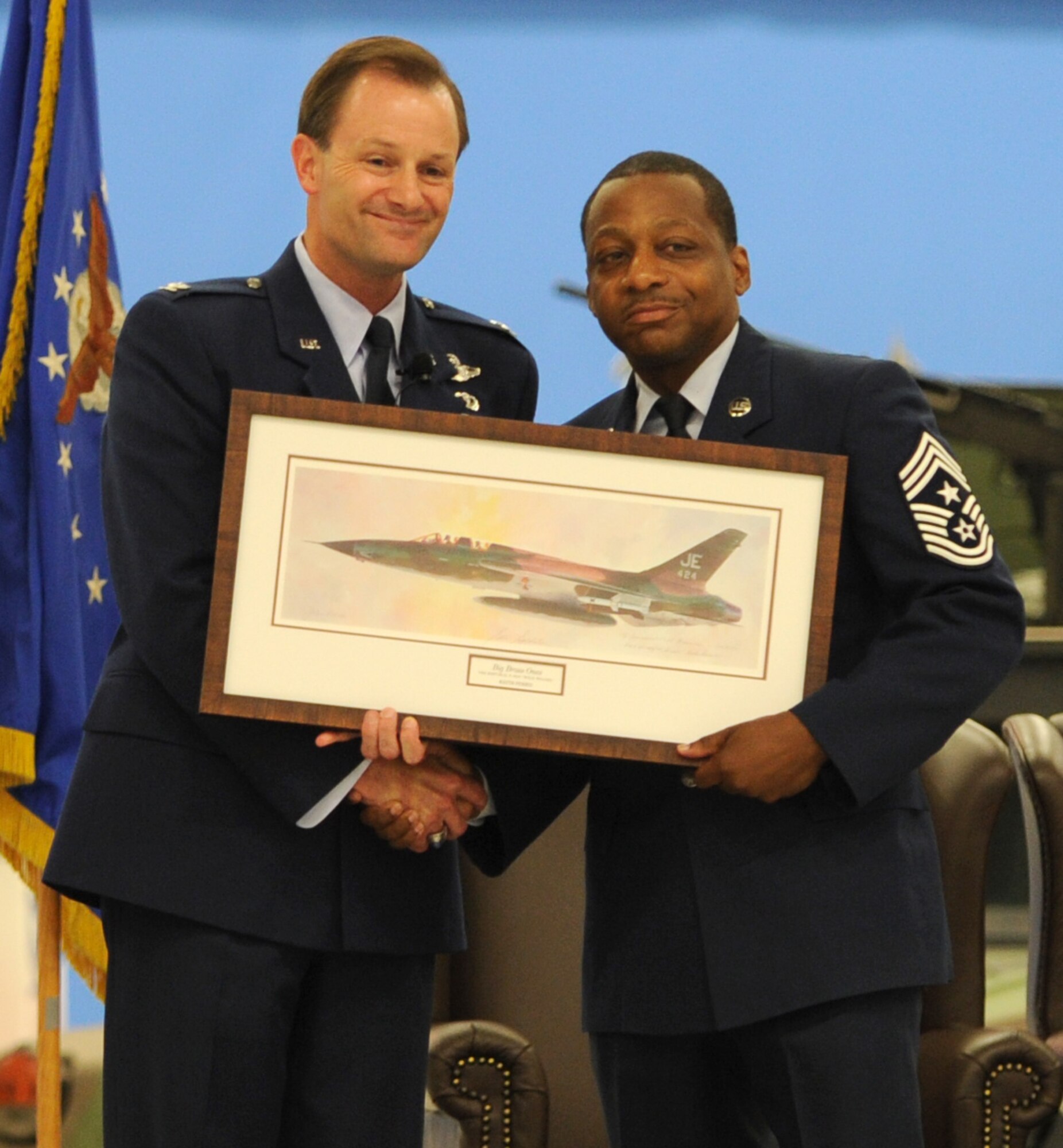 Colonel Ken Rizer, 11th Wing/Joint Base Andrews commander, presents Chief Master Sgt. Anthony Brinkley, 11th Wing/Joint Base Andrews command chief, with a painting of a "Wild Weasel" F-105 during Brinkley's retirement ceremony June 8, 2012. F-105 #62-4424 "Crown 7" was the aircraft assigned to Major John Revak, pilot, and Major Stan Goldstein, electronic warfare officer, of the 44th Tactical Fighter Squadron, 388th Tactical Fighter Wing based at Korat, Thailand. These brave and dedicated crews purposely drew fire in advance of the strike force in order to locate, intimidate or destroy enemy defenses.  Rizer compared Brinkley's dedication to doing "the right thing" despite personal or professional consequences to the mission of the "Wild Weasles."  (U.S. Air Force Photo by Staff Sgt. Torey Griffith)