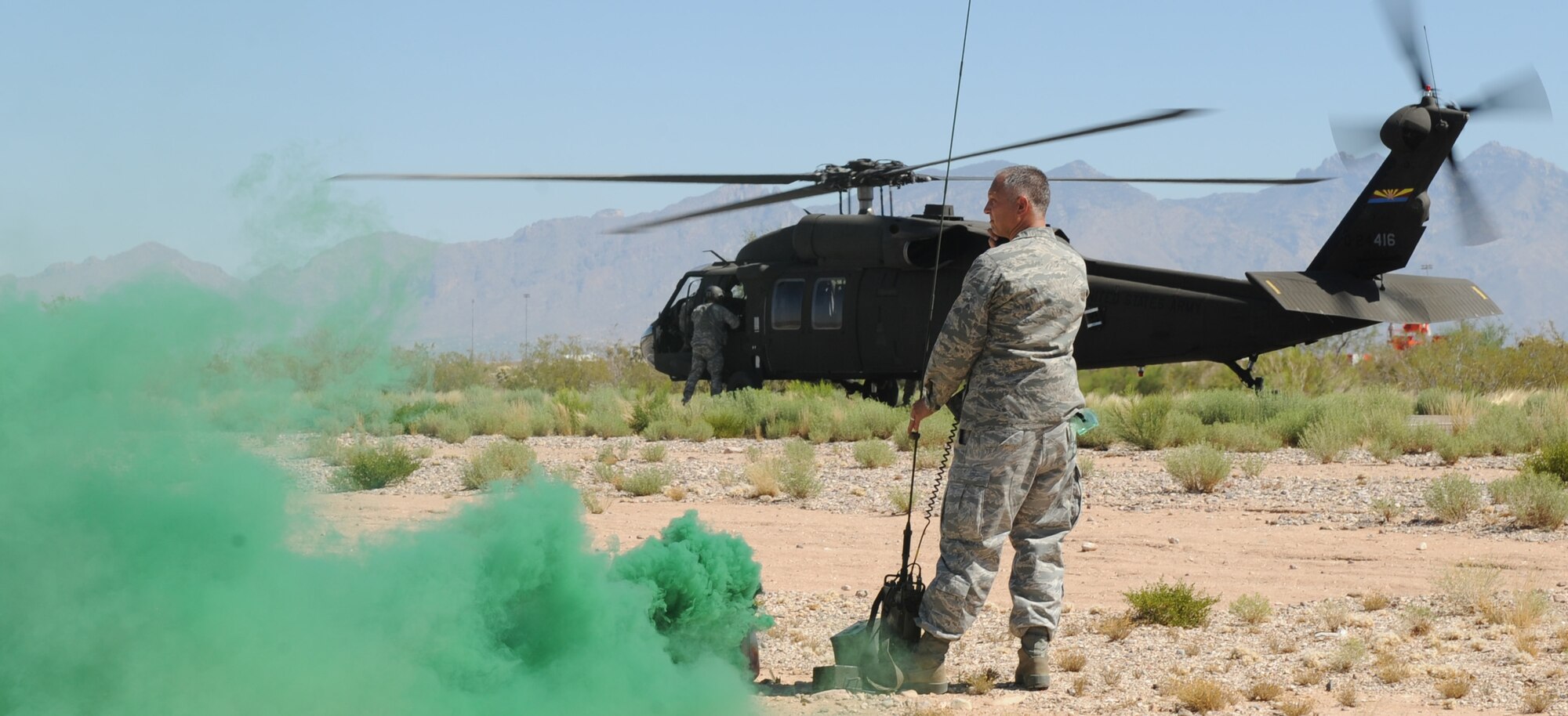U.S. Air Force Lt. Col. Kjall Gopaul, 355th Mission Support Group deputy commander, radios in to the air crew of a UH-60 Black Hawk during helicopter pre-deployment training at Davis-Monthan Air Force Base, Ariz. June 7. During this training, military members were taught how to get on and off a helicopter quickly and safely, how to provide cover for an aircraft and how to sling-load cargo. (U.S. Air Force photo by Senior Airman Brittany Dowdle/released)