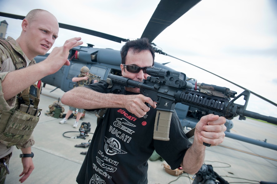 Lee Bivens, U.S. Air Force Art Program artist, aims an M-4 assault rifle with assistance from U.S. Air Force Staff Sgt. Ryan Onley, 38th Rescue Squadron pararescueman, June 8, 2012, at Moody Air Force Base, Ga. Bivens graduated from the University of South Carolina in 1987 with a degree in Arts and Business and has been commissioned to create artwork by various Atlanta pro sports organizations and athletes. Through the Air Force Art Program, he now travels the world creating artwork telling the Air Force story. (U.S. Air Force photo by Staff Sgt. Jamal D. Sutter/Released)