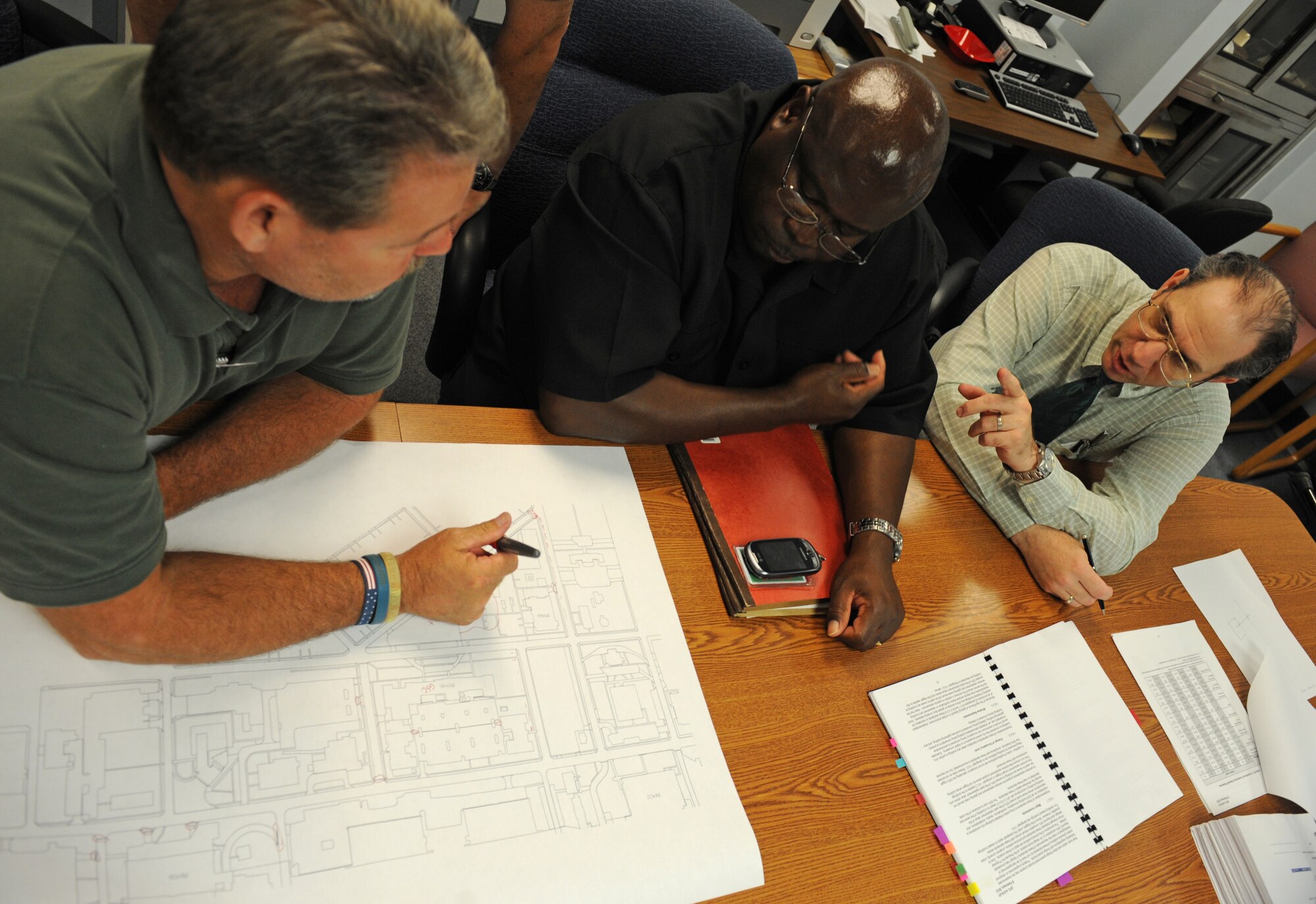 Tony Cyr, left, 2nd Civil Engineer Squadron Programming Flight chief, Lorenzer Brown, 2nd Bomb Wing Anti-Terrorism Force Protection, and Nathan Tracer, 2 CES Programming Flight architect, discuss base infrastructure security concerns on Barksdale Air Force Base, La., June 7. By looking over the drawing plans of the base infrastructure with the subject matter experts, the group is able to address concerns that do not meet Air Force standards. (U.S. Air Force photo/Airman 1st Class Benjamin Gonsier)(RELEASED)