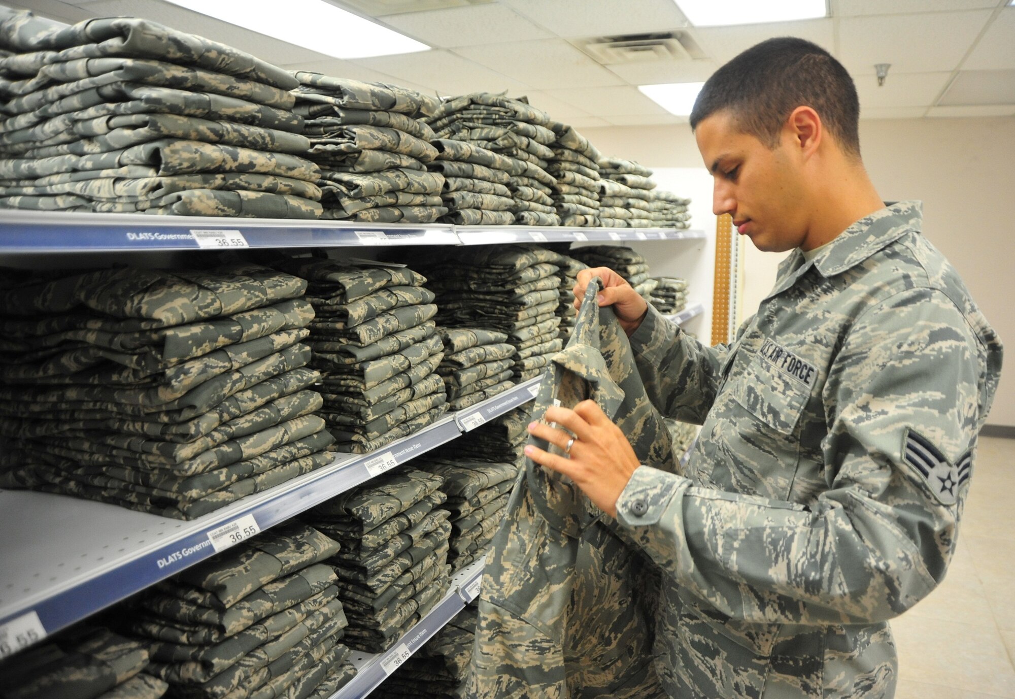 Senior Airman Adam Dkhili, , Headquarters Air University A4/6, Logistics and Communications computer programmer searches for a new set of summer weight Airman Battle Uniforms at clothing sales. Maxwell AFB is one of 17 Air Force bases to receive the new, lighter uniforms early, while others will receive the new uniform in 2013. The new material, the 50-50 nylon-cotton blend used in the Army combat uniform, weighs 6½ ounces per square yard, compared with 7½ ounces for the older ABU. Since the Air Force is not forcing Airmen to replace their uniforms, a special clothing allowance will not be provided. Costs are expected to be approximately $80.00 for the blouse and pants. For more information, call 953-7505. (Air Force photo by Senior Airman Christopher Stoltz)