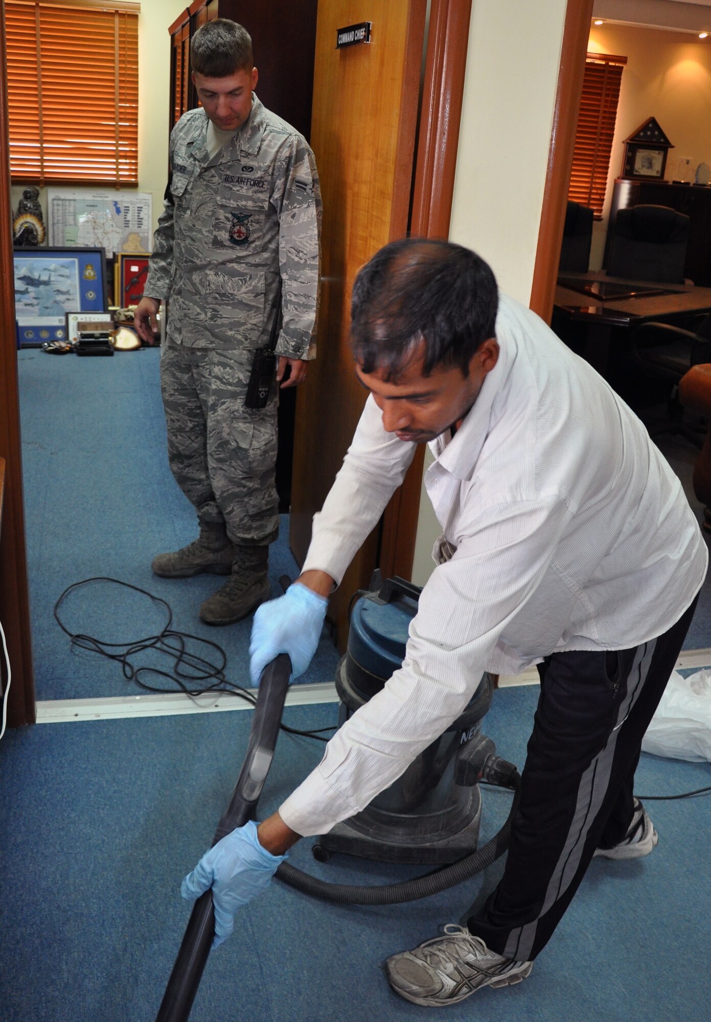Airman 1st Class Drew Thatcher, 386th Expeditionary Civil Engineer Squadron Force Protection Flight’s Custodial Worker Escort Team, watches contractors clean the 386th Air Expeditionary Wing command offices June 7, 2012, in an undisclosed location in Southwest Asia.  Thatcher and the other CWE escort and monitor the cleaning of all buildings around base, ensuring operational security while under the guise of "just standing around." Thatcher is a Seattle, Wash., native deployed from the 673rd Civil Engineering Squadron from Elmendorf Air Force Base, Alaska. (U.S. Air Force photo/Tech. Sgt. Stacy Fowler/Released)