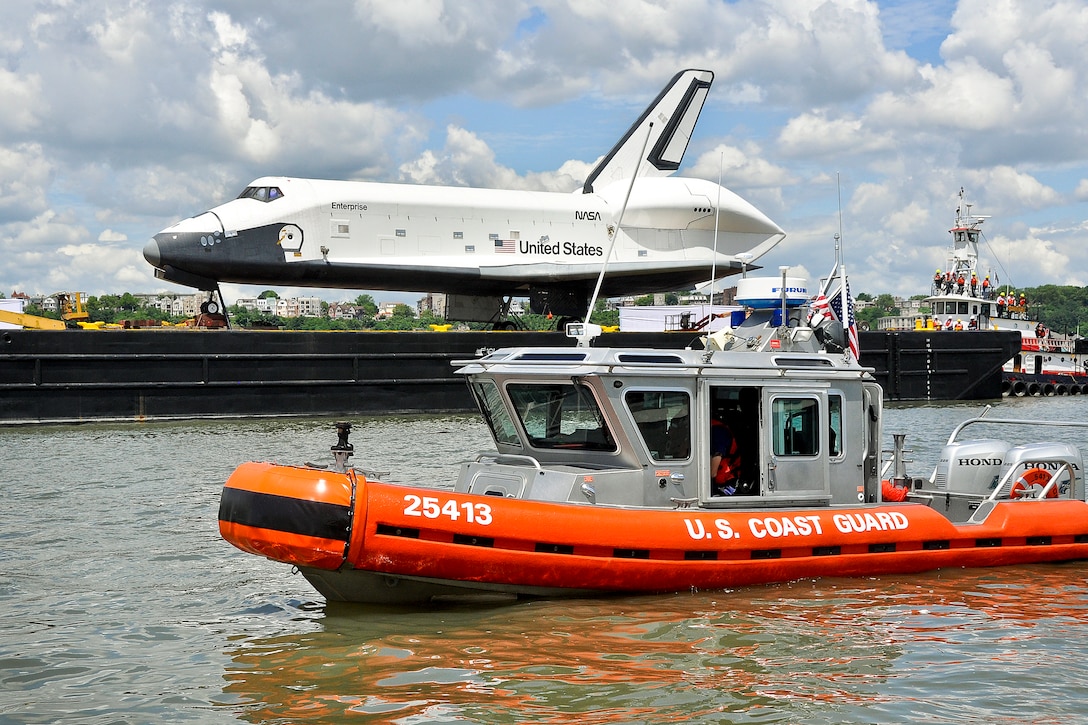 A Coast Guard boat crew from Station New York enforces a safety zone around a barge carrying the retired Space Shuttle Enterprise while it transits through New York Harbor to the Intrepid Sea, Air and Space Museum, June 6, 2012.