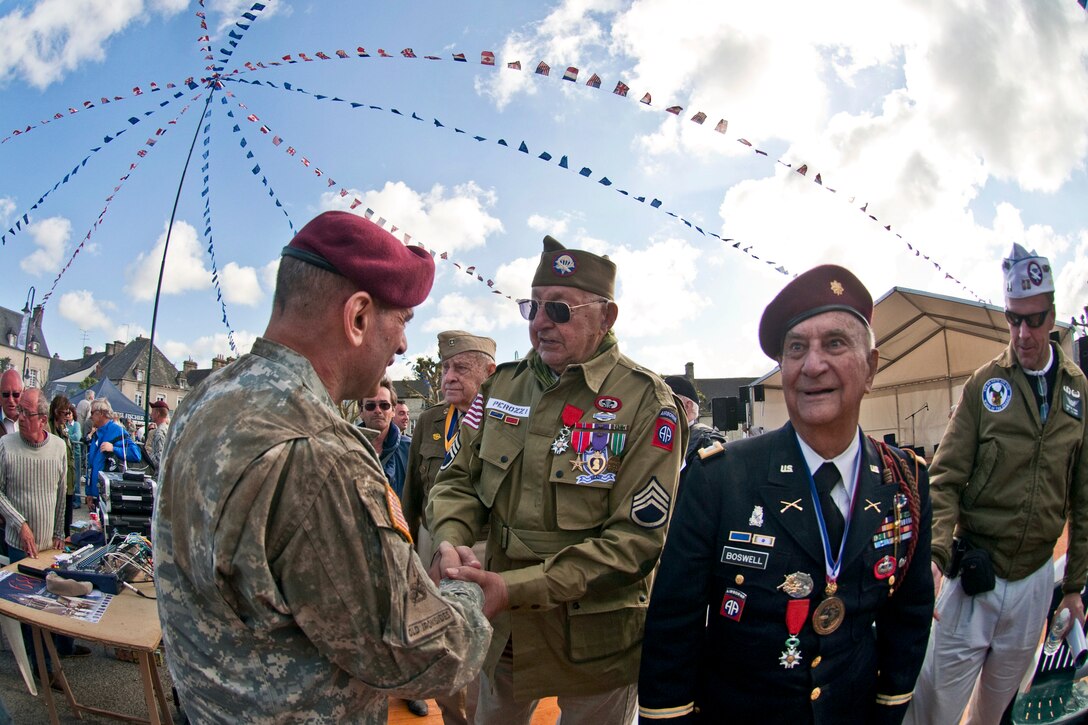 U.S. Army Maj. Gen. Jeffrey A. Jacobs, commanding general of the U.S. Army Civil Affiars & Psychological Operations Command, shakes hands with John Perozzi, a World War II and D-Day veteran who served with the 82nd Airborne Division, after a ceremony honoring him and other WWII veterans in Sainte-Mere-Eglise, France, June 3, 2012.