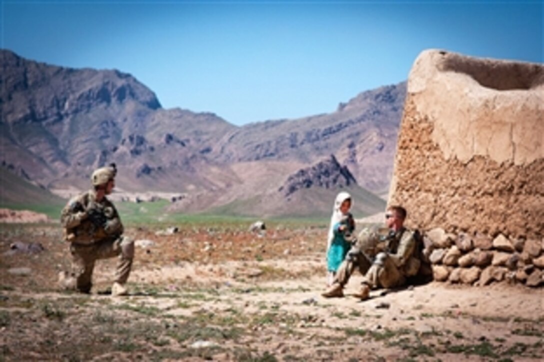 A U.S. paratrooper watches as a fellow U.S. soldier gives candy to a Afghan girl during a  break in an operation Afghanistan's Ghazni province, June 2, 2012. The soldiers are assigned to the 82nd Airborne Division’s 1st Brigade Combat Team.