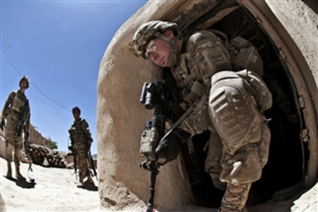 A U.S. paratrooper exits an Afghan building after searching it during a combat operation in Afghanistan's Ghazni province, June 2, 2012. The soldier is assigned to the 82nd Airborne Division’s 1st Brigade Combat Team. Outside, a fellow paratrooper and an Afghan soldier keep watch over the remainder of the compound.