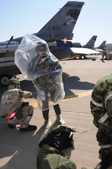 SIOUX FALLS, S.D. -- After exiting his F-16 aircraft, a pilot with the South Dakota Air National Guard gets assistance from a crew chief donning his over cape in a simulated contaminated area during the 2012 Operational Readiness Exercise, June 9.  The exercise is being held to assess the readiness of the unit.  (National Guard photo by Tech. Sgt. Quinton Young) (Released)