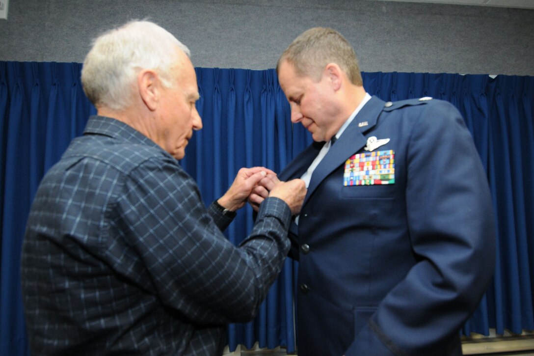 JOINT BASE ELMENDORF-RICHARDSON, Alaska - Retired U.S. Air Force Col. Joseph Coniglio fastens on a command pin to the lapel of his son's, Lt. Col. Scott Coniglio, June 6, 2012. A command pin worn above the name tag signifies that the person wearing the pin above the nametag is a current commander. Lt. Col. Coniglio is the new commander of the 176 Maintenance Group. He will be in charge of more than 200 Airmen responsible for the maintenance of 176 Wing's airplanes and helicopters. National Guard Photo by Tech. Sgt. Jennifer Theulen.