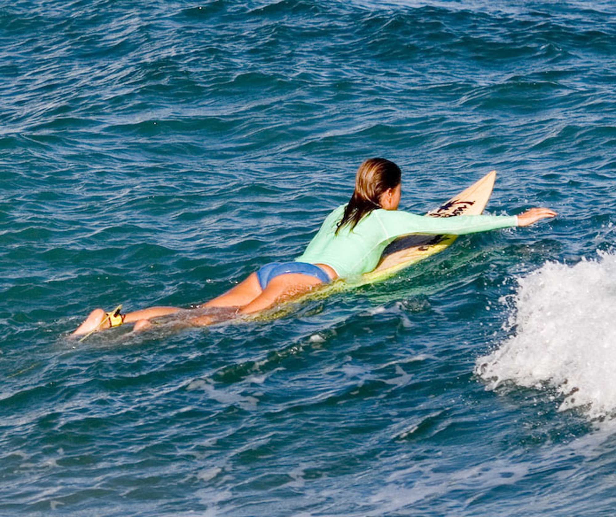 Lying prone on a surfboard can cause hyperextension of the spine and lead to a rare injury called surfer myelopathy. Symptoms include back pain, tingling sensation in the legs, loss of feeling in the legs, inability to walk, paralysis and urinary retention. (Photo by Kanaka Menehune)