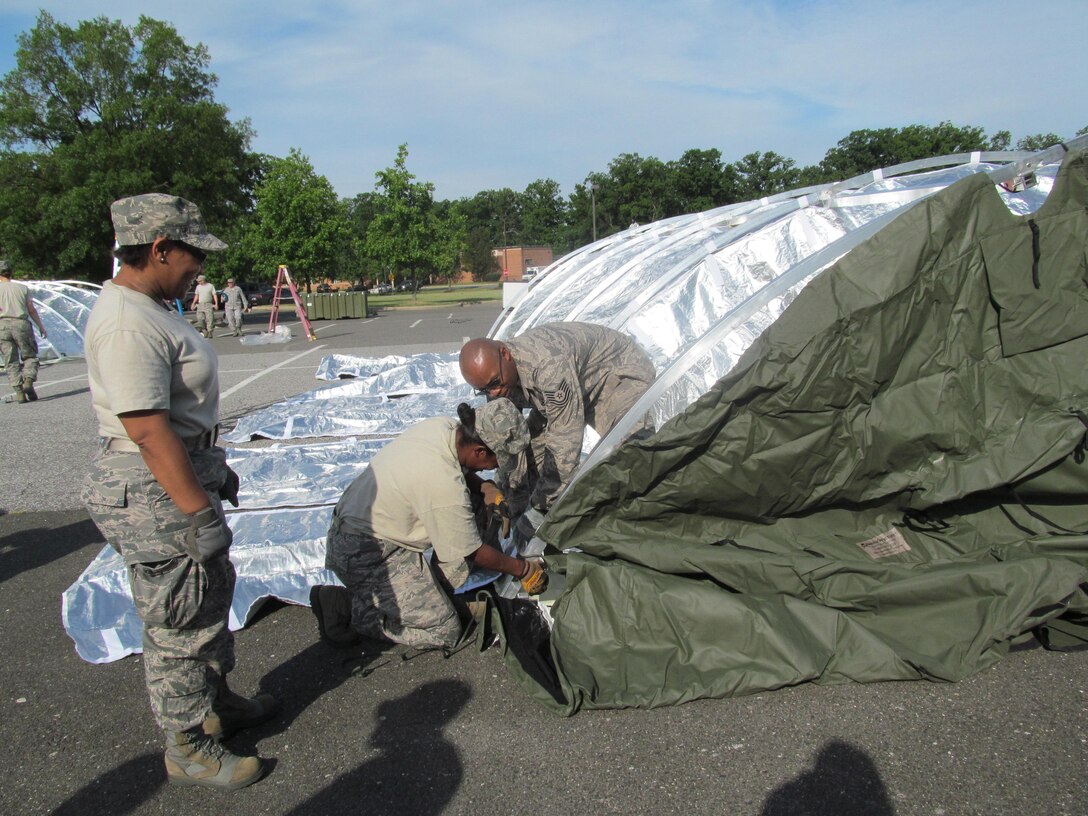 Major Traci Carter, 779th Medical Group operations officer observes as Master Sgt. Tacita Griffin, 779th Medical Group Family Health Clinic group practice manager and Tech. Sgt. Anthony Bennett, 779th Medical Group, information systems security officer, work as a team to put together a wall of the 25-bed field hospital during an exercise on May 6, 2012. The 779th Medical Group on Joint Base Andrews conducted an exercise to hone their disaster-response skills. (AF Photo by Melanie Moore)