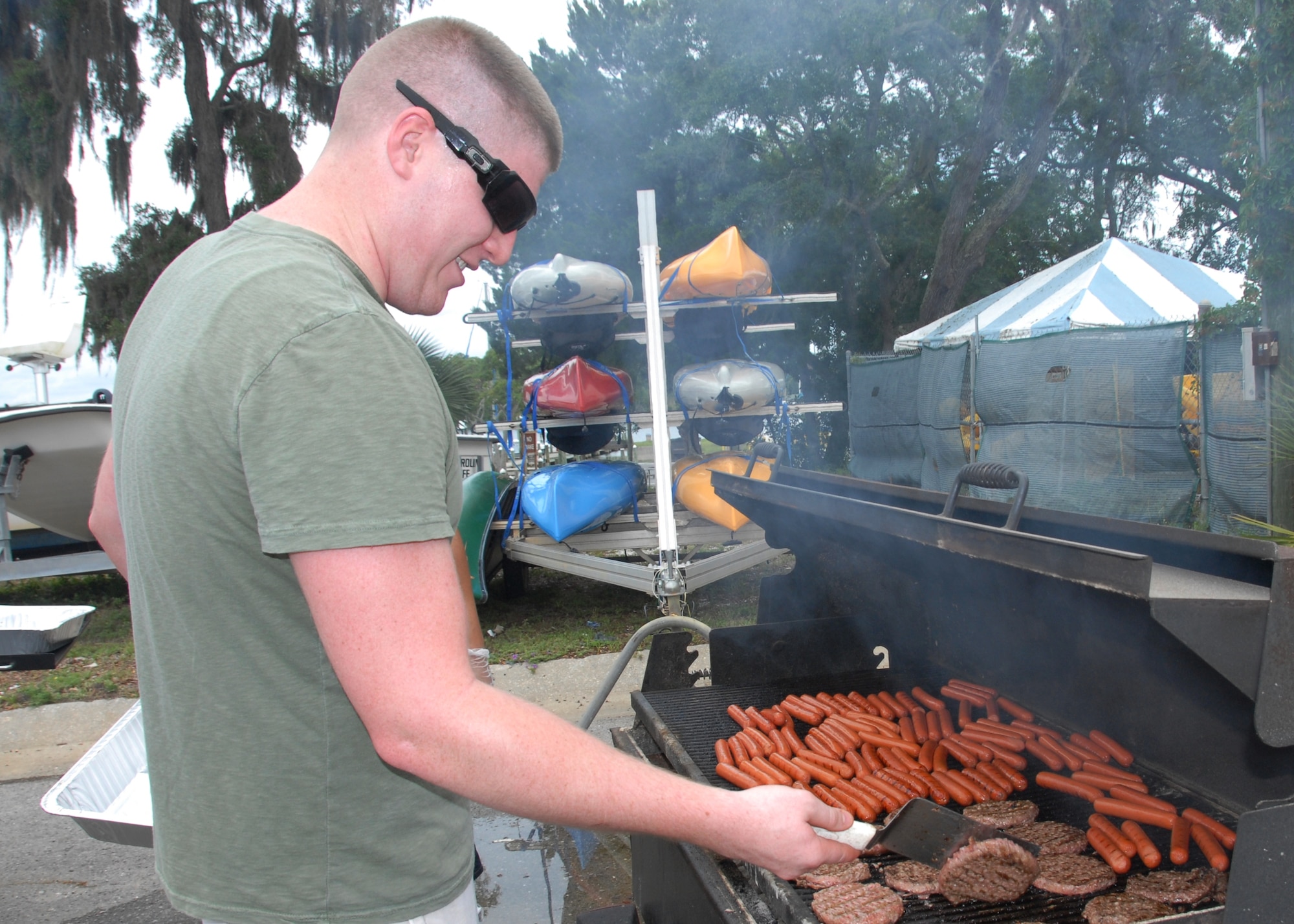 Airman 1st Class Caige Chapman, a member of the 96th Inpatient Unit Intensive Care Flight, flips a burger at the Team Eglin Picnic at Post’l Point June 8. The event featured free food and entertainment for Eglin personnel and families, including a water slide, bouncy house, climbing wall, bungee jumping and horseback riding. (U.S. Air Force photo/Kevin Gaddie)