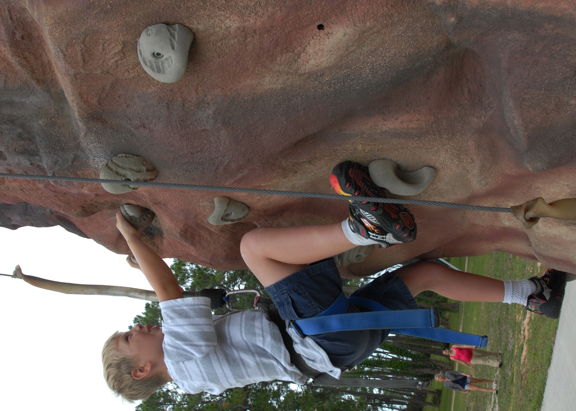 Gage Smith scales the rock climbing wall at the Team Eglin Picnic at Post’l Point June 8.  The event featured free food and entertainment for Eglin personnel and families, including a water slide, bouncy house, climbing wall, bungee jumping and horseback riding. (U.S. Air Force photo/Kevin Gaddie)
