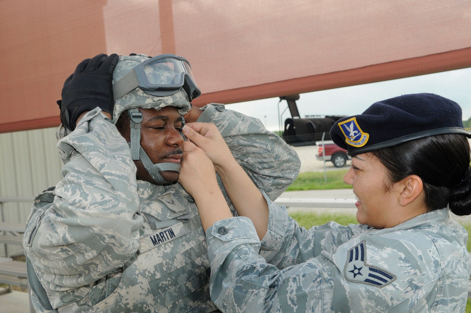 Senior Airman Celina Reyes, 902nd Security Forces Squadron police services administrator, helps Airman 1st Class Carl Martin installation police officer adjust his helmet chin strap prior to beginning Shoot, Move and Communicate training at Camp Talon on Joint Base San Antonio- Randolph, June 7.  (U.S. Air Force Photo by Don Lindsey)