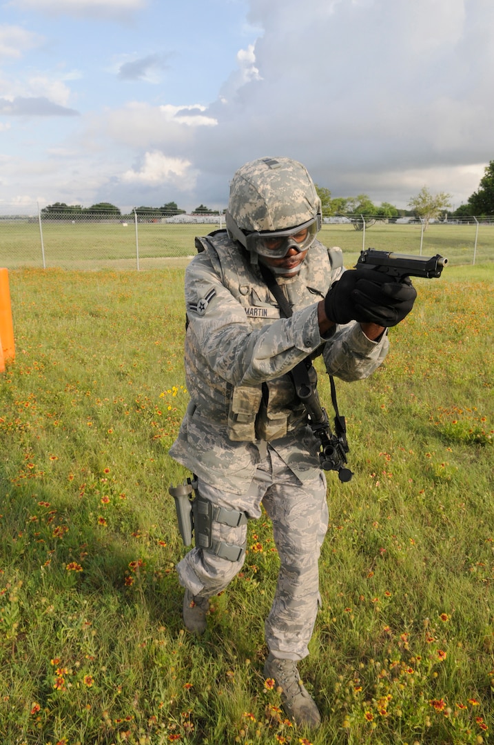 Airman 1st Class Carl Martin, 902nd Security Forces Squadron installation police officer, points his pistol while running after a perpetrator during Shoot, Move and Communicate training at Camp Talon on Joint Base San Antonio- Randolph, June 7.  (U.S. Air Force Photo by Don Lindsey)