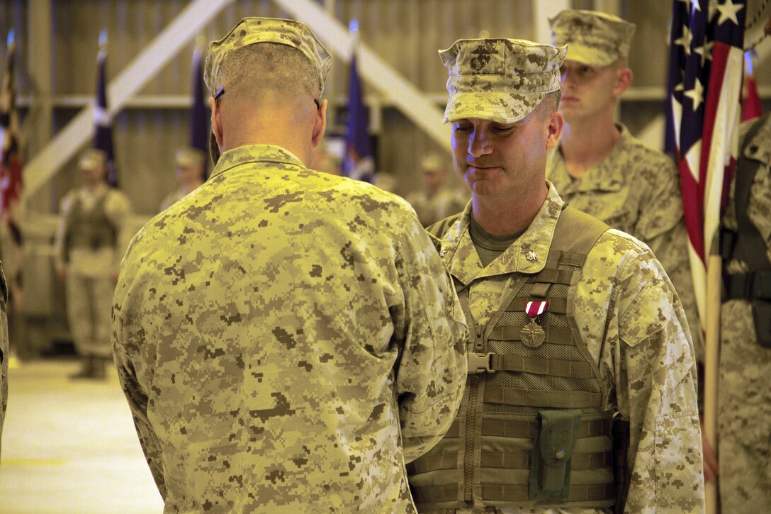 Col. Christopher J. Mahoney, Marine Aircraft Group 12 commanding officer, presents the Meritorious Service Medal to Lt. Col. Michael C. Taylor, right, outgoing  Marine Wing Support Squadron 171 commanding officer, at the squadron's change of command ceremony at Marine All-Weather Fighter Attack Squadron 242's hangar here, June 12, 2012. The ceremony marked transfer of command from Taylor to incoming MWSS-171 commanding officer, to Lt. Col. Howard Eyth.
