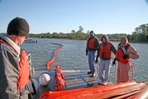 Members of the Facility Response Team observe the booms being towed out to the water to ensure there are no tangles during a simulated oil spill training exercise Oct. 29, at the station's fuel pier.