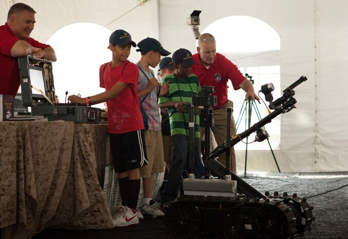 Michael Santiago, 12-year-old Cleveland native, controls a Marine Corps robotic system at the Marine Corps Systems Command display tent outside the Great Lakes Science Center in Cleveland in June. The display was part of Marine Week Cleveland events. Explosive ordnance disposal and infantry Marines use the robots, which have been in use in combat zones since 2001, to protect Marines and prevent injuries. The Marine Corps is currently developing a remote that units can carry with them which will control both ground robots and unmanned aircraft as well. More than 750 Marines were in Cleveland all week displaying Marine aircraft, vehicles and equipment, as well as interacting and sharing with the public the values and character of the Marine Corps. One of the culminating events was a Marine Air Ground Task Force demonstration at Burke Lakefront Airport, which showcased Marines' ability to assault from ship-to-shore via ground and air.
