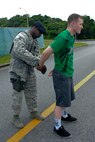 U.S. Air Force Staff Sgt. Gregory Beamon, 18th Security Forces Squadron response force leader, simulates arresting U.S. Air Force Airman 1st Class Todd Holly, 18th Wing Public Affairs broadcaster, during a vandalism video spot filmed on Kadena Air Base, Japan, June 7, 2012. Recently more than $11,000 in damages to military housing has been reported in the last six months. As school closes out for the summer, vandalism is expected to rise. Security forces officials remind base residents to lock up their cars and homes and report any suspicious activity. (U.S. Air Force photo/Airman 1st Class Hailey R. Davis)