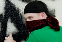 U.S. Air Force Airman 1st Class Todd Holly, 18th Wing Public Affairs broadcaster, notices security forces approaching after being spotted during a vandalism video spot taken on Kadena Air Base, Japan, June 7, 2012. The vandalism commercial highlights vandalism and the consequences of law violations on Kadena. Since the year began, more than $11,000 in damages to military housing have been reported. Base residents should report suspicious activity to the law enforcement desk at 634-2475 or 634-2476. (U.S. Air Force photo illustration/Airman 1st Class Hailey R. Davis)