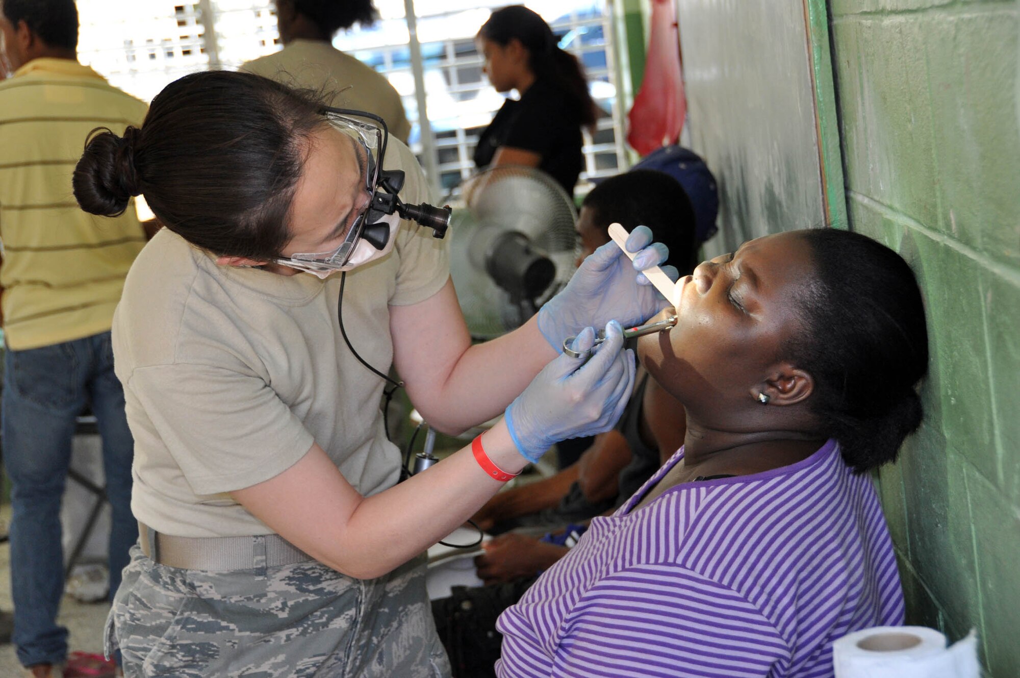 (Left) Capt. Jennifer Fong, 926th Aerospace Medicine Squadron dentist, examines a patient in the Dominican Republic last month during a humanitarian mission. Fong was part of a U.S. Air Force Reserve and Air National Guard dental team that saw 656 people over 15 days and conducted more than 825 tooth extractions. (U.S. Air Force photo/Maj. Myla Abejuela)