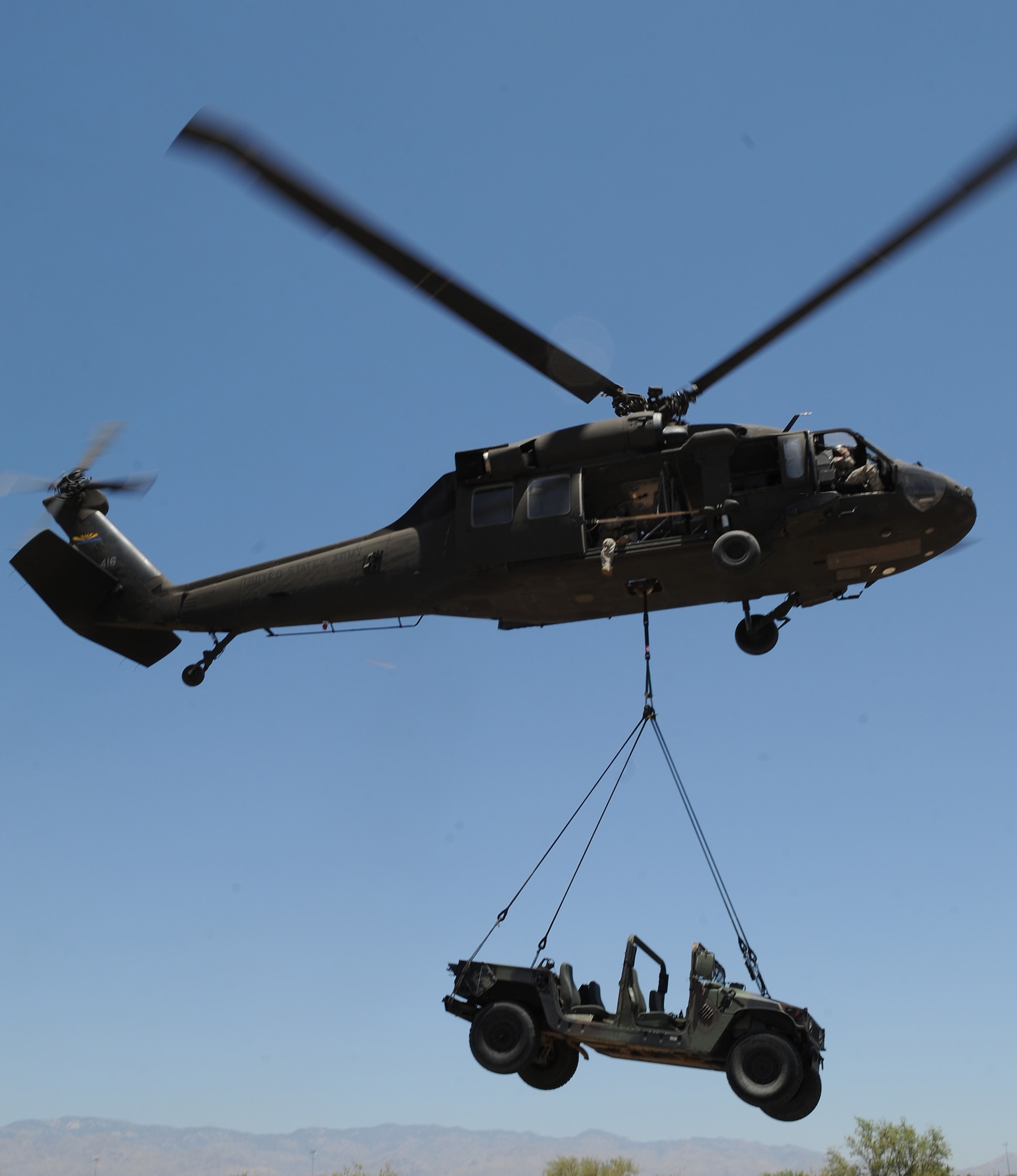 U.S. Army soldiers from the 2nd Battalion, 285th Aviation Regiment, Arizona Army National Guard sling-carry a M-1097 high mobility multipurpose wheeled vehicle at the helicopter pre-deployment training at Davis-Monthan Air Force Base, Ariz., June 7, 2012. The HMMWV weighs 6,000 pounds and was carried twice during this training. (U.S. Air Force photo by Senior Airman Brittany Dowdle/released)