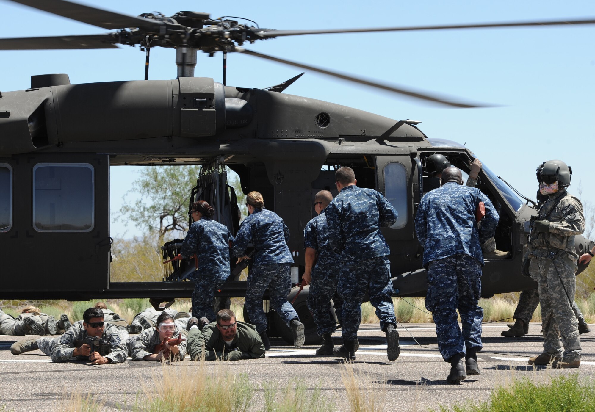 U.S. Navy sailors load on board a UH-60 Black Hawk while other participants of the helicopter pre-deployment training provide cover for the aircraft and their brothers-in-uniform at Davis-Monthan Air Force Base, Ariz., June 7, 2012. This training was offered to all local branches of the military. (U.S. Air Force photo by Senior Airman Brittany Dowdle/released)