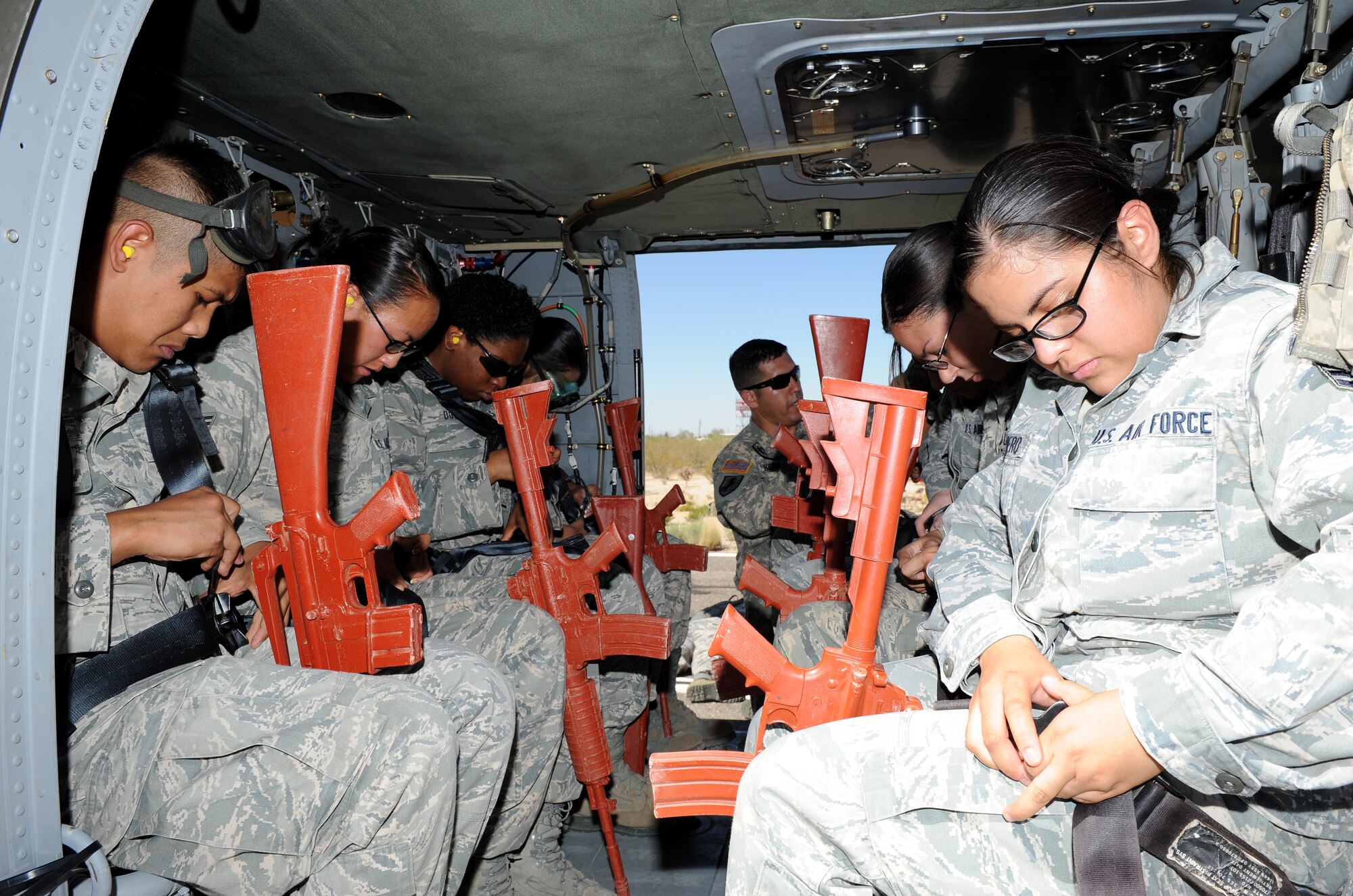 Participants of the helicopter pre-deployment training practice putting on their safety belts in a UH-60 Black Hawk at Davis-Monthan Air Force Base, Ariz., June 7, 2012. During this training, military members were taught how to get on and off a helicopter quickly and safely, how to provide cover for aircraft and how to sling-load cargo. (U.S. Air Force photo by Senior Airman Brittany Dowdle/released)